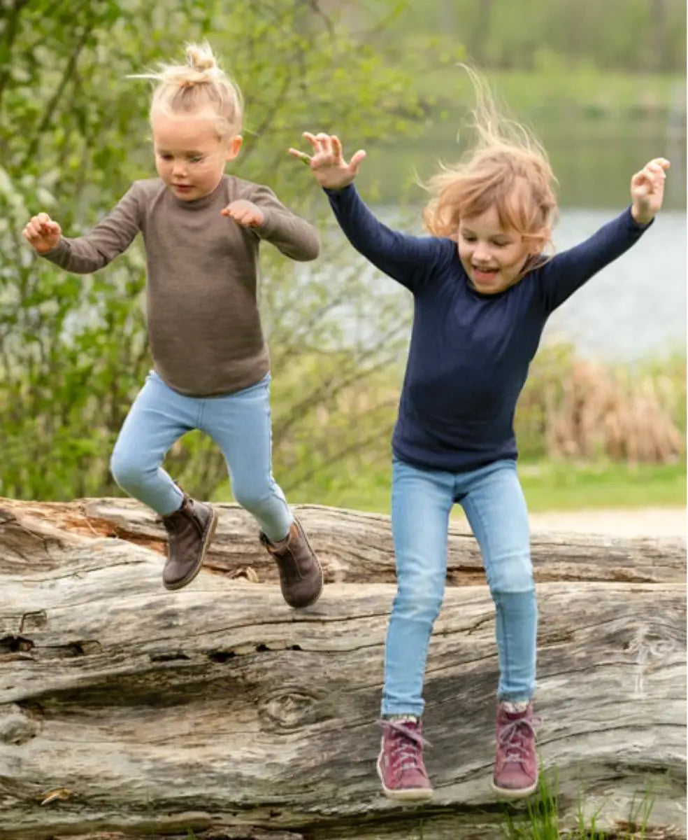 Two Girls Jumping down a log wearing Engel Sweaters