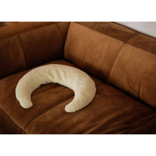 Senger White crescent-shaped nursing pillow on a brown leather couch