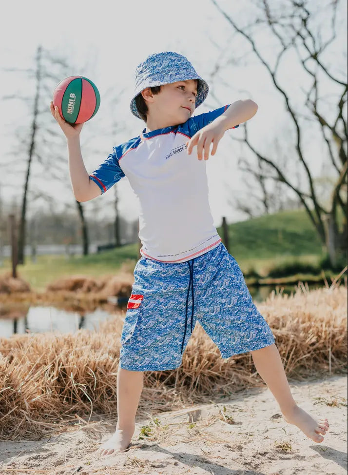 Boy in swim trunk throwing football